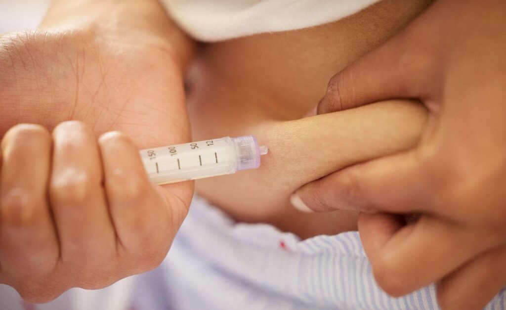 A hand grips a syringe, indicating preparation for an injection or medical treatment
