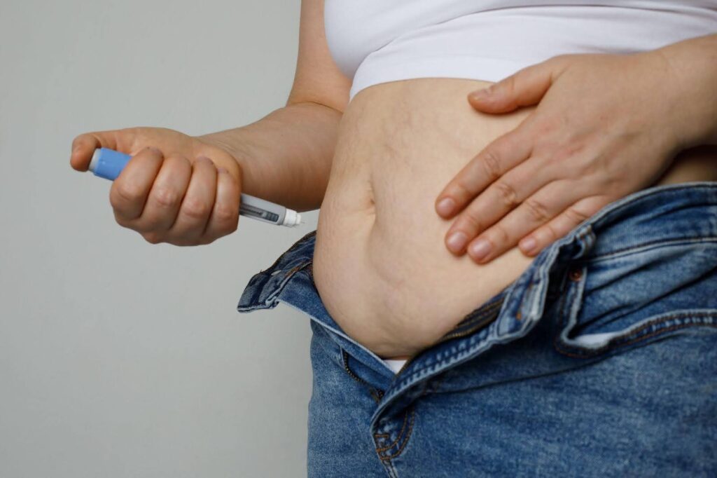 A woman holds a thermometer to her belly, symbolizing health awareness