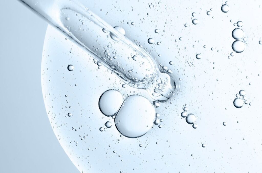 A close-up view of a single drop of water resting on the surface of a clear glass