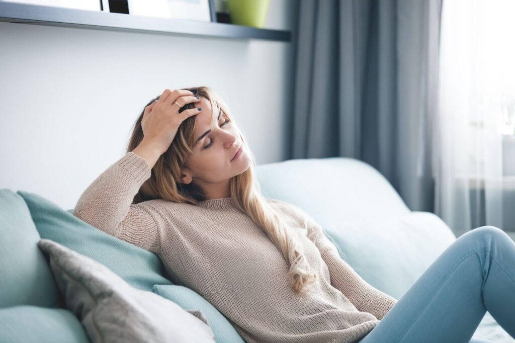 A woman on a couch with her head in her hands looking distressed