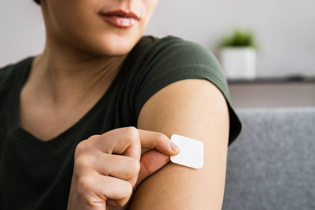 A woman holds a small patch on her arm showcasing a skin treatment or medical device