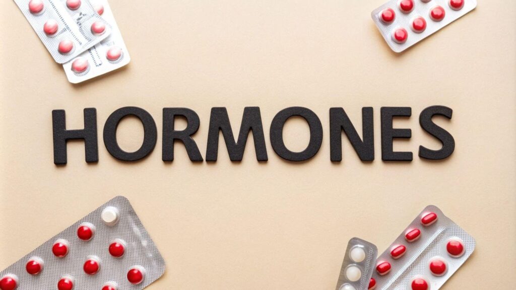 Pills and tablets labeled hormones arranged on a beige background