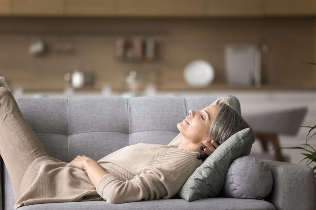 A woman lounges on a couch appearing relaxed and at ease in a warm and inviting living space