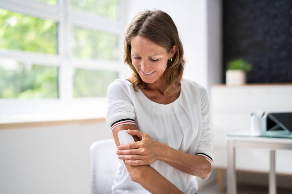 A woman raises her arm touching it with her other hand showcasing a gesture of contemplation or thought